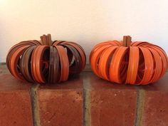 two orange pumpkins sitting on top of a brick wall