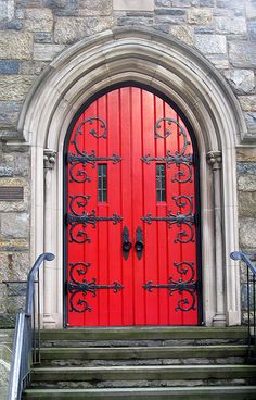 a red door with iron bars on it and stairs leading up to the front entrance