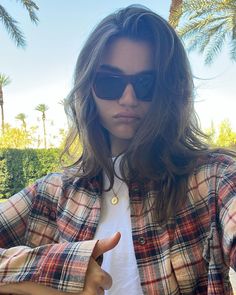 a woman with sunglasses on giving the thumbs up while standing in front of palm trees