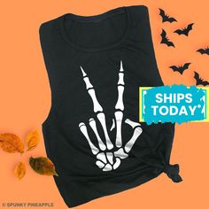 Skeleton Peace Fingers Muscle Tank, Halloween Workout Muscle Tee, Womens Halloween Shirt * SIZING * Please see images with size chart details for ordering. Available in sizes: S, M, L, XL and XXL. This style of muscle tee runs on the small side, we do suggest ordering up 1 to 2 sizes for a looser fit. * SHIPPING * All orders are printed by hand and shipped out within 1 business day. All items are shipped via USPS First Class Mail (3 to 5 days transit time).   Need it sooner? Shipping upgrades available at checkout (transit time is 1 to 3 days based on your location -- USA only) * OUR PROCESS * We print our shirts by hand with 100% eco-friendly water based inks. Water based inks produce a super soft, breathable print with unmatched comfort and durability. We DO NOT USE vinyl.    * EXCHANGE Halloween Punk Stretch Tops, Halloween Punk Top With Skull Print, Black Stretch Halloween Tops, Black Stretch Tops For Halloween, Black Stretch Top For Halloween, Black Skull Print Top For Halloween, Halloween Stretch Tops With Letter Print, Black Stretch T-shirt For Halloween, Halloween Skull Letter Print Tops