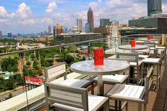 tables and chairs on top of a roof with cityscape in the background