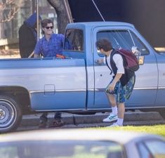 two young men standing in the back of a pick up truck next to each other