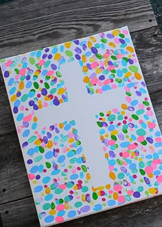 a cross made out of confetti on top of a piece of paper