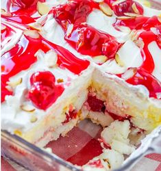 a cake with cherries and white frosting in a glass dish on a checkered table cloth