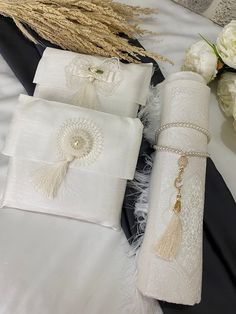 four white napkins with tassels and beads on them sitting on a bed