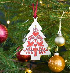 a christmas tree ornament hanging from the top of a pine tree with ornaments around it