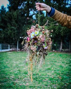 a person is holding up a bouquet made out of plants and flowers in the grass