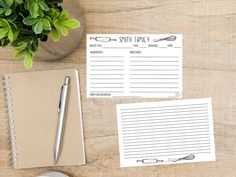 two notepads sitting on top of a wooden table next to a pen and plant