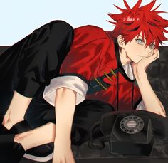 a man with red hair laying on the ground next to an old phone and telephone