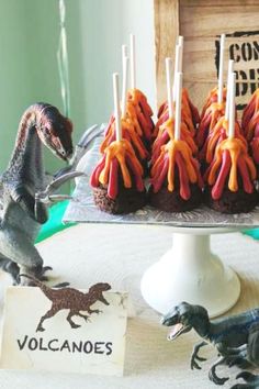 an assortment of dinosaur treats on a cake plate