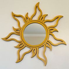 a mirror that is sitting on the wall next to a white wall with a yellow sun design