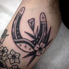 a black and white photo of a tattoo with scissors on it's arm, in the shape of a horseshoe