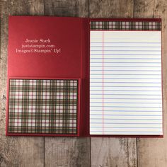 a red notebook with lined paper inside on a wooden table next to an empty notepad