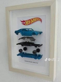 two hot wheels cars are in a shadow box on the wall next to each other