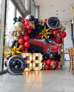 a red car surrounded by balloons in the shape of an 80th birthday balloon display