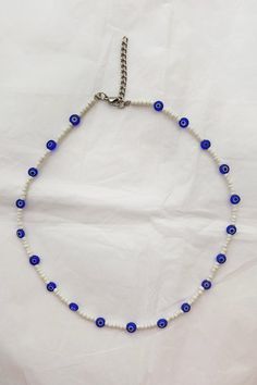 a blue and white beaded necklace is displayed on a white sheet with a silver chain