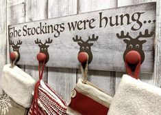 three stockings hanging from hooks on a wooden wall with the words, the stockings were hung