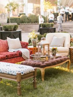 an outdoor seating area with couches, chairs and tables in the grass at a wedding