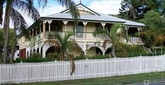 an old house with white picket fence and palm trees