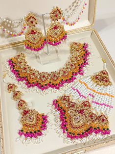 an assortment of beaded jewelry is displayed in a white box with gold trimmings