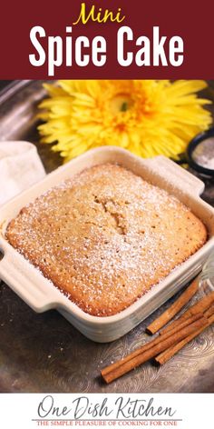 a close up of a cake in a pan with cinnamon sticks and flowers behind it