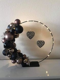 a black and silver wreath with ornaments hanging from it's sides on a shelf