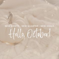 a white pumpkin sitting on top of a bed next to the words hello, october