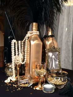 a table topped with bottles and glasses filled with pearls next to a candle holder on top of a table