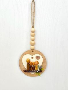 A Precious One-of-a-Kind Rock Family of 4 Rock Art Decor Hanging Handcrafted on 4" Circle Wood with light oak stained.  Makes as a Lovely Hanging Gift for Anytime of the Year: for Anniversary, Mother's Day, Father's Day, Birthday, Christmas, Valentines, Housewarming to a sweet family of 4, etc.. Or add the precious hanging decoration to your own home decor, decorate on doors, pull-knobs, on the wall, hang on curtain hooks, on a Christmas tree, hang on a lamp switch, set on books, display on coffee table, a decor tray, etc. Possibilities are endless.  Circular wood plus the beading the ornament is approximately 7" high and 4" wide. With twine the overall height is just over 10" high. The loop opening is near 3". This precious decoration ornament is made with small and medium size mixed rock Guitar Pebble Art, Books Display, Rock Family, Decor Tray, Ornament Storage, Lamp Switch, Family Of 4, Decor Hanging, Wood Hearts