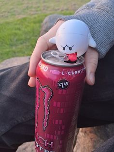 a person holding a can with a stuffed animal on top of it's head