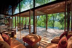 a living room with couches and tables in front of an open air kitchen area