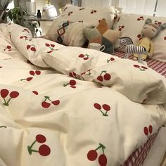 an unmade bed with cherries on it and two stuffed animals in the middle