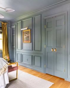 a bedroom with blue painted walls and wooden flooring, along with a gold framed painting on the wall