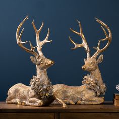 two golden deer statues sitting on top of a wooden table