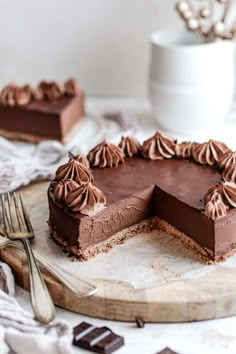 a chocolate mousse cake on a wooden platter with a slice cut out