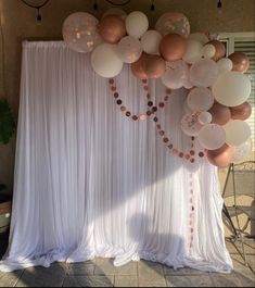 the balloon arch is decorated with white and rose gold balloons