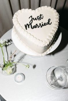 a heart shaped cake sitting on top of a table next to wine glasses and flowers