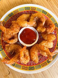 fried shrimp with ketchup on a colorful and patterned plate atop a wooden table