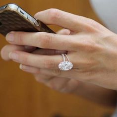 a woman is using her cell phone while wearing an engagement ring with a diamond on it