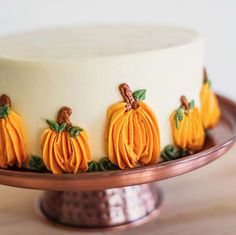 a cake decorated with pumpkins and leaves on a plate