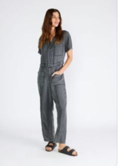 A classic utility-style jumpsuit in an ash grey wash tencel. Tencel Relaxed fit Short sleeve Long straight leg Collared neckline Button front top Zip fly closure Front patch pockets Back patch pocket Utility jumpsuit A jumpsuit to wear on repeat all spring and summer long. Featuring the perfect relaxed fit, our utility-style one-piece is crafted from lightweight tencel and features a button-front top and collared neckline. Short sleeves keep things breezy, while the straight long leg pairs well Utility Style Denim Jumpsuit With Short Sleeves For Work, Short Sleeve Denim Utility Jumpsuit For Workwear, Gray Jumpsuits And Rompers With Pockets For Spring, Gray Spring Jumpsuits And Rompers With Pockets, Fall Workwear Cargo Jumpsuits And Rompers, Cargo Style Jumpsuits And Rompers For Workwear In Fall, Casual Cargo Jumpsuits And Rompers For Work, Casual Short Sleeve Jumpsuits And Rompers With Buttoned Pockets, Casual Workwear Overalls With Short Sleeves