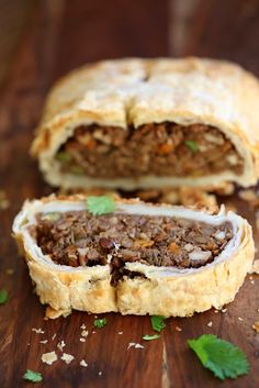 a meat filled pastry sitting on top of a wooden table