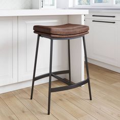 a brown leather seat on a black metal bar stool in a white kitchen with wood flooring