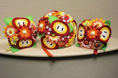 three decorative items are sitting on top of a white plate with orange and yellow flowers