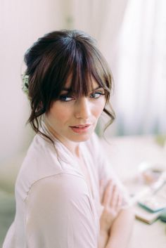 a woman sitting on a bed with her arms crossed and looking off to the side