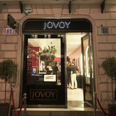 the entrance to jovoy is lit up at night with people walking in and out