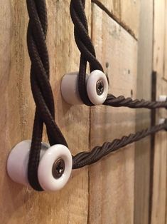 two white and black earbuds attached to a wooden wall with rope on it