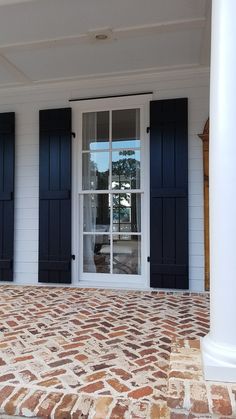 the front entrance to a white house with black shutters