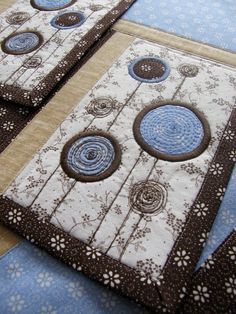 three quilted coasters with blue and brown circles on them sitting on a table