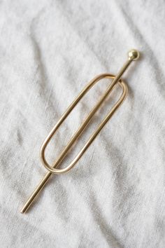 Made by hand out of recycled solid brass in a California studio. To use, weave through your hair to create tension. Great for half-up or side swept styles for medium to thick hair or to hold Details subtly textured Finish 2.25 inch slightly curved elongated oval sleeve with 3 inch stick pin Crafted from recycled brass in California Brass Care: This piece will naturally darken over time. Always remove before entering pools or hot tubs as chlorine may affect the finish. Buff with a polishing cloth